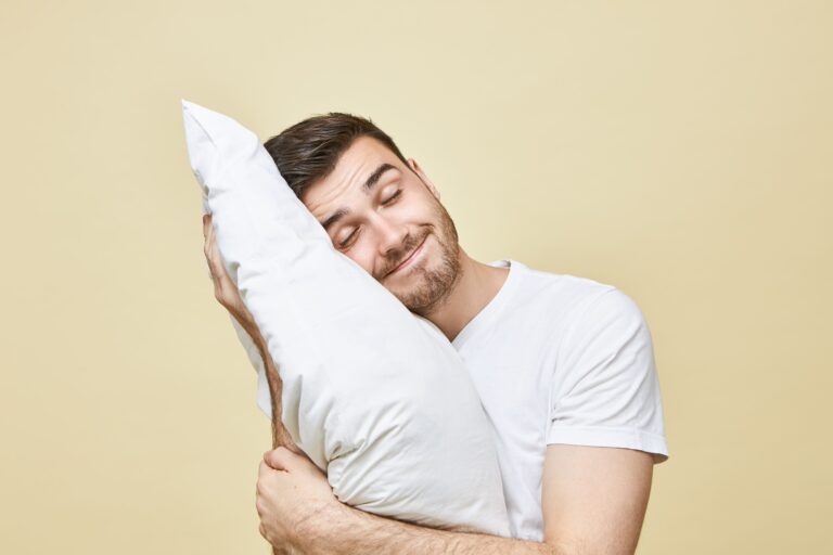 Homem abraçando travesseiro relaxado.