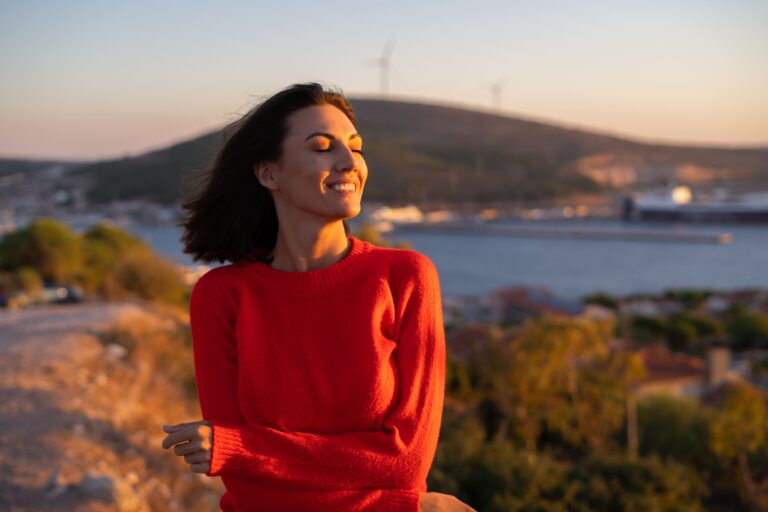 Mulher em suéter vermelho ao pôr do sol.